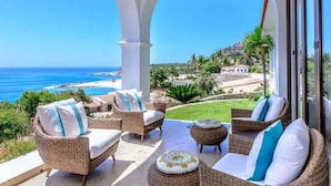 A balcony with wicker furniture, a view of the sea, and a mountainous landscape. - Beachfront Palmilla Villa with Private Beach Walk (San José del Cabo)