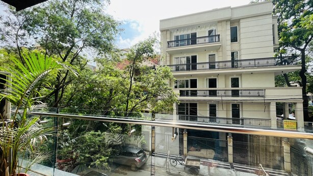 Un immeuble à plusieurs étages doté de balcons, entouré d’une végétation luxuriante.