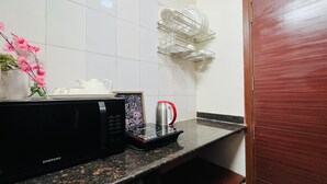 Une cuisine équipée d’un four à micro-ondes, d’une bouilloire et d’une machine à café, le tout posé sur le plan de travail.