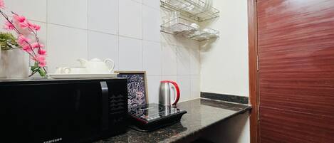 Una cocina con microondas, hervidor y cafetera sobre la encimera.