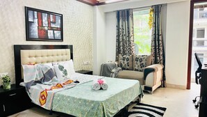 Une chambre à coucher comprenant un lit, un canapé, une fenêtre avec des rideaux et une œuvre d’art accrochée au mur.