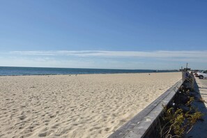 A sandy beach with a wooden walkway and a clear blue sky.