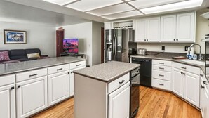 Eine moderne Küche mit weißen Schränken, einem Edelstahlkühlschrank und Holzboden.
