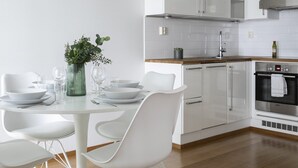 A modern kitchen with white cabinetry, a wooden countertop, and a round dining table with white chairs. - 1BR apartment with SPA in Kamppi Center (Helsinki)