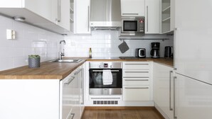 A modern kitchen with white cabinets, stainless steel appliances, and a wooden countertop. - 1BR apartment with SPA in Kamppi Center (Helsinki)