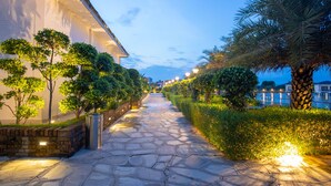 A stone pathway flanked by trees and a building with illuminated windows. - Lumbini Palace Resort (Dayanagar)