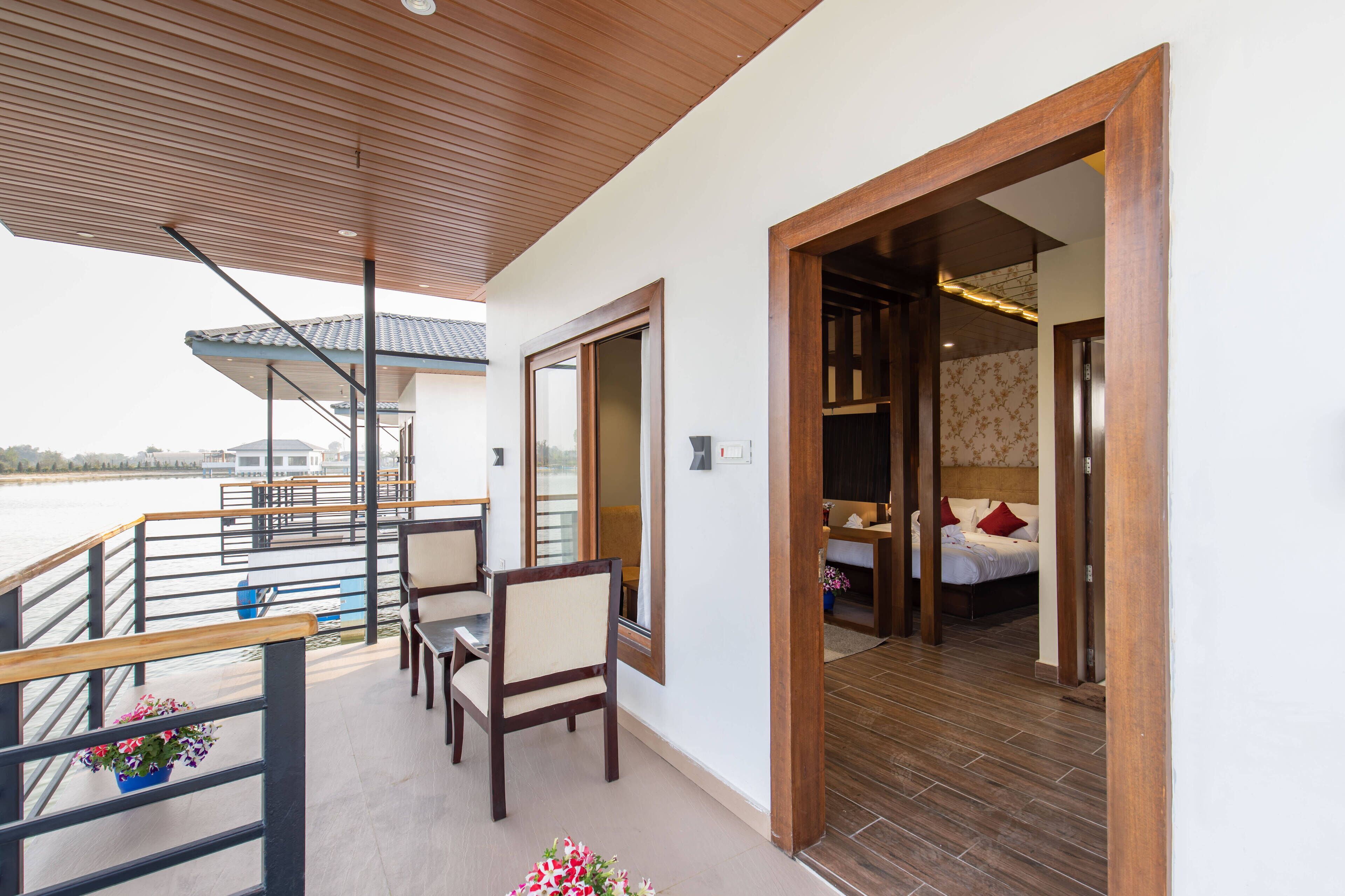 A balcony with wooden railings, a dining area with chairs, and a view of the water.