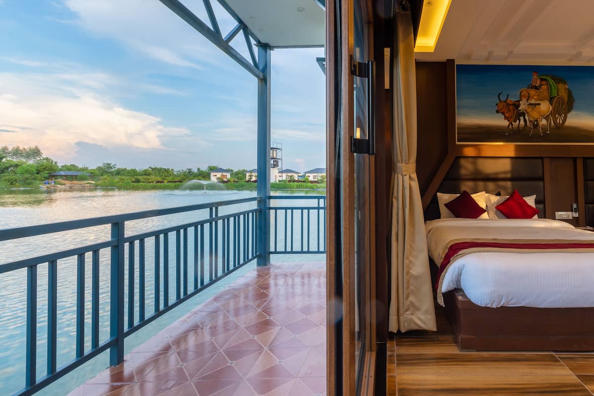 Ein Zimmer mit einem Bett, einem Gemälde und Blick auf einen Fluss.