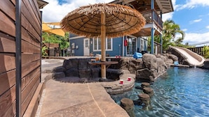 A pool area with a thatched umbrella, a slide, and a seating area with a table and chairs. - Two homes w/ pool and hot tub near 3 beaches, Kihei (Kihei)