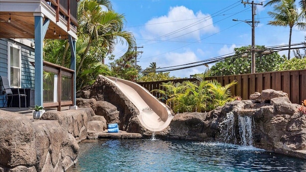 A pool with a water slide, surrounded by rocks and palm trees. - Two homes w/ pool and hot tub near 3 beaches, Kihei (Kihei)