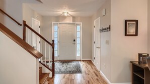 A hallway with a wooden staircase, a white door with frosted glass panels, and a patterned rug on the floor. - Clean+Cozy+Close to 85 & 316 | Pets (Lawrenceville)