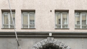 En byggnads entré med en valvformad öppning i sten, en dörr med nummer och ett litet trappsteg som leder upp till entrén.