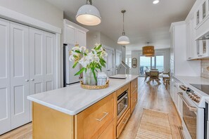 A modern kitchen with white cabinets, wooden countertops, and a central island with a vase of flowers.