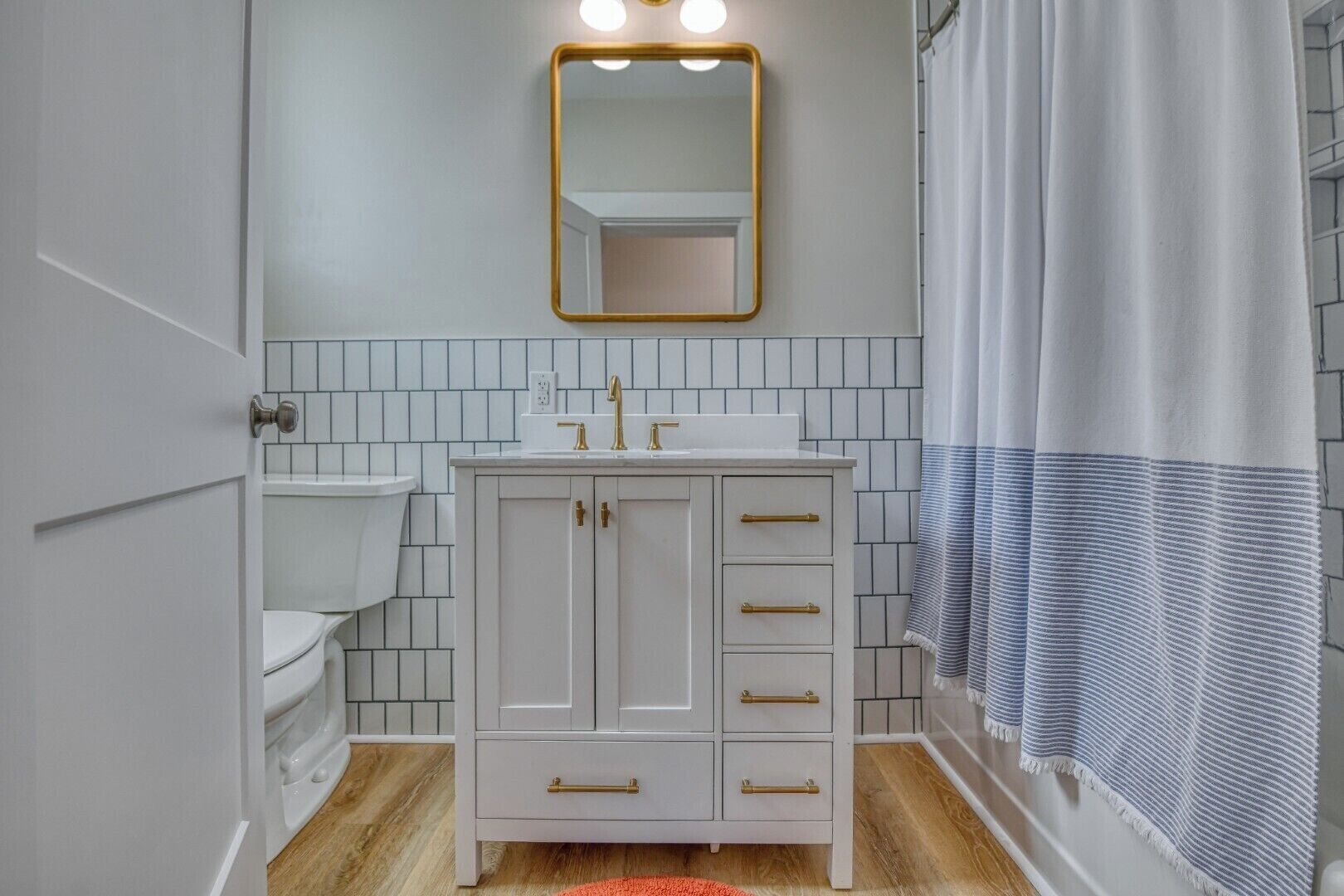 A bathroom with a white sink, a mirror with a gold frame, and a shower curtain.