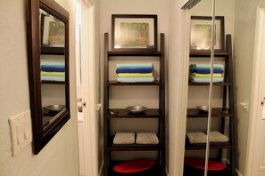 A narrow hallway with wooden shelves holding towels and bowls. - Kihei Bay Surf #218 Renovated, Near Beach, Shared Hot Tub, Inner Courtyard (Kihei)