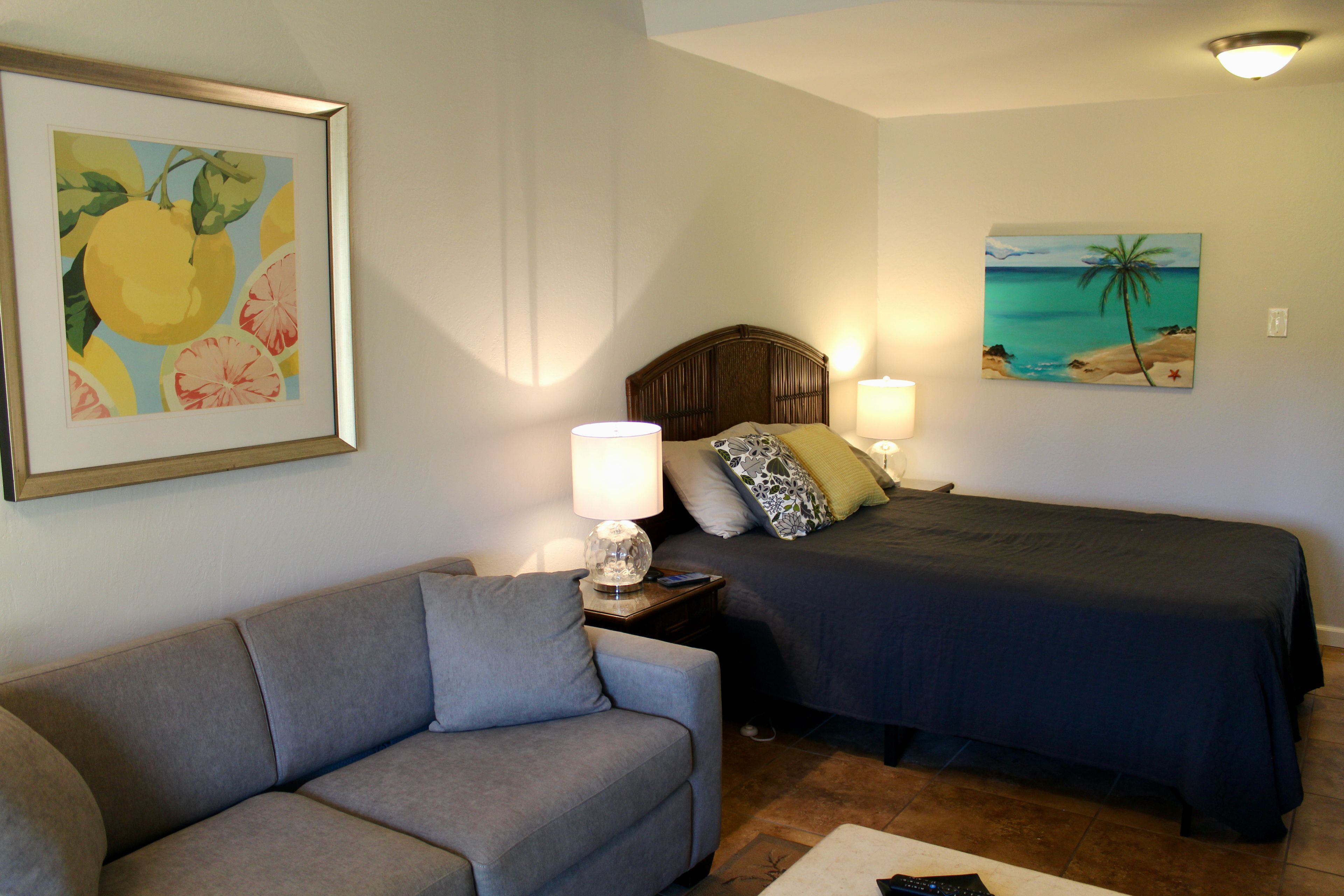 A bedroom with a bed, bedside table, lamp, and a framed painting on the wall.