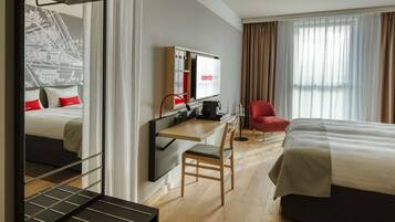 Una habitación de hotel con una cama, un escritorio con computadora, una silla y un televisor.