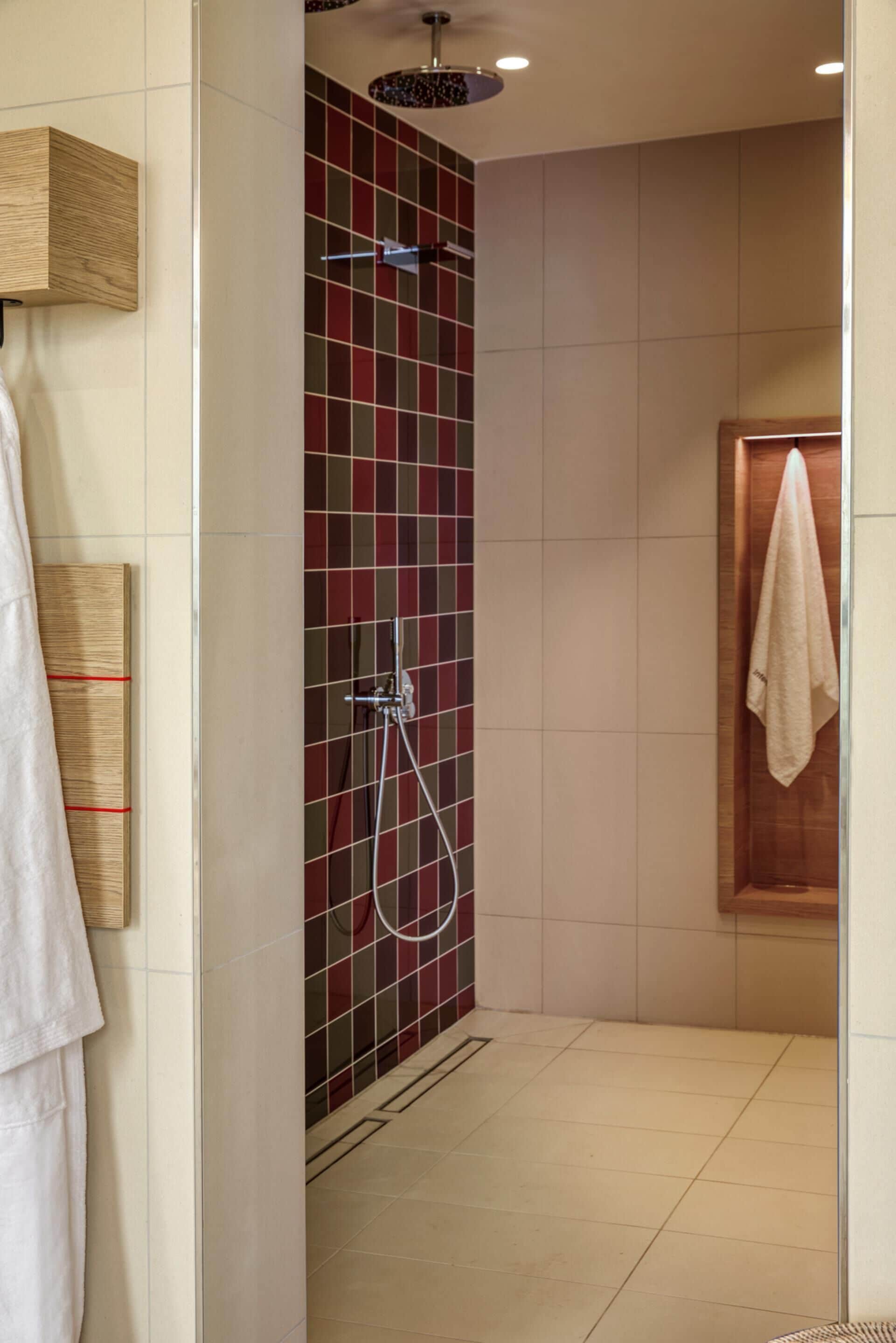 Un área de ducha con pared de azulejos, una puerta de madera y una toalla colgada en la puerta.