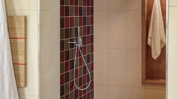 Un área de ducha con pared de azulejos, una puerta de madera y una toalla colgada en la puerta.