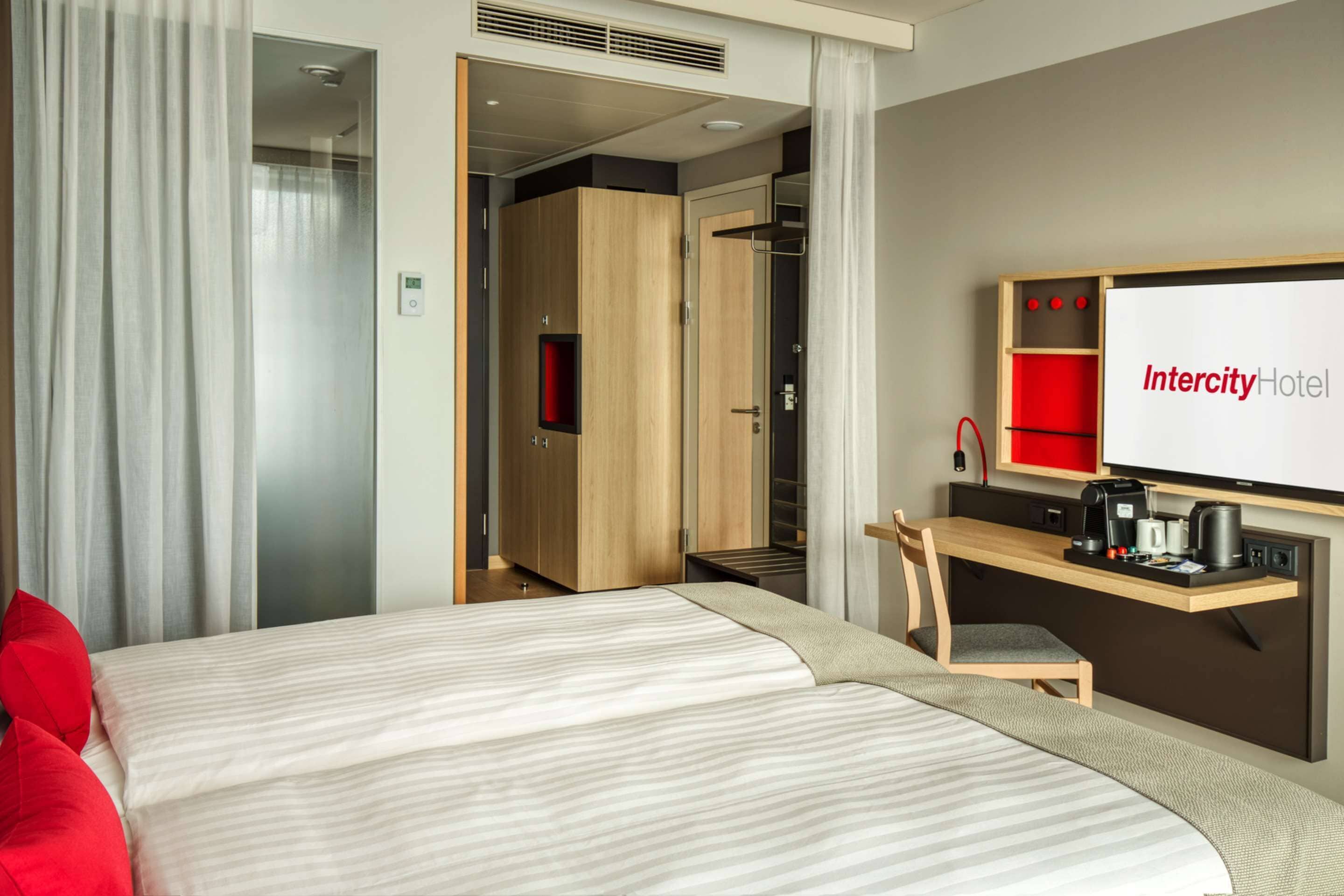 A hotel room with two beds, a desk with a coffee maker, and a mirror.