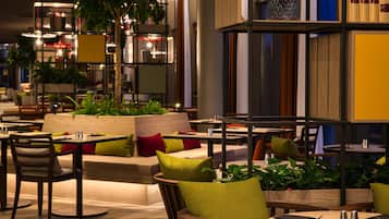 Een moderne zithoek met ronde tafels, comfortabele stoelen en verschillende planten.