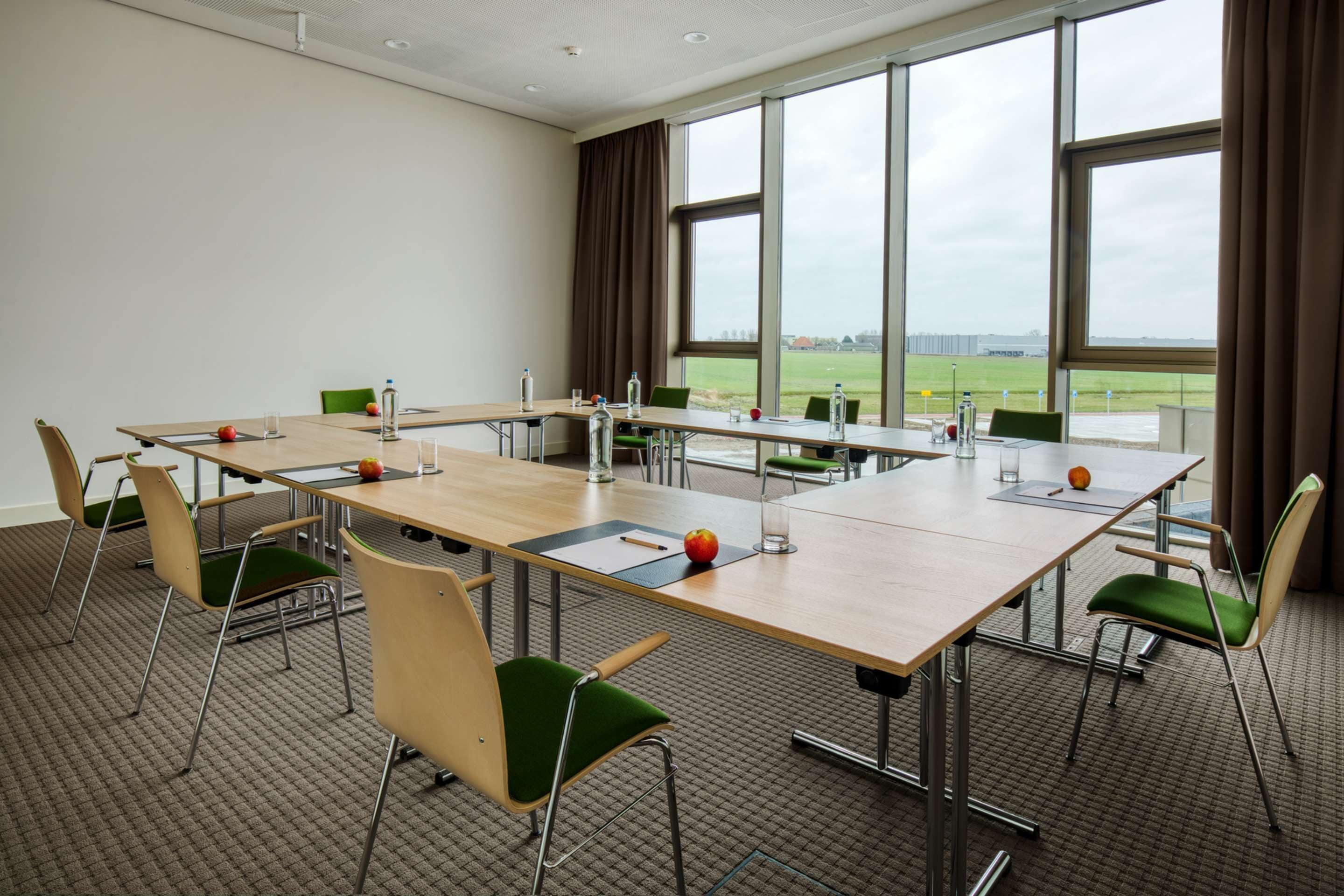 Un salón de conferencias con una larga mesa, sillas y vistas al exterior.