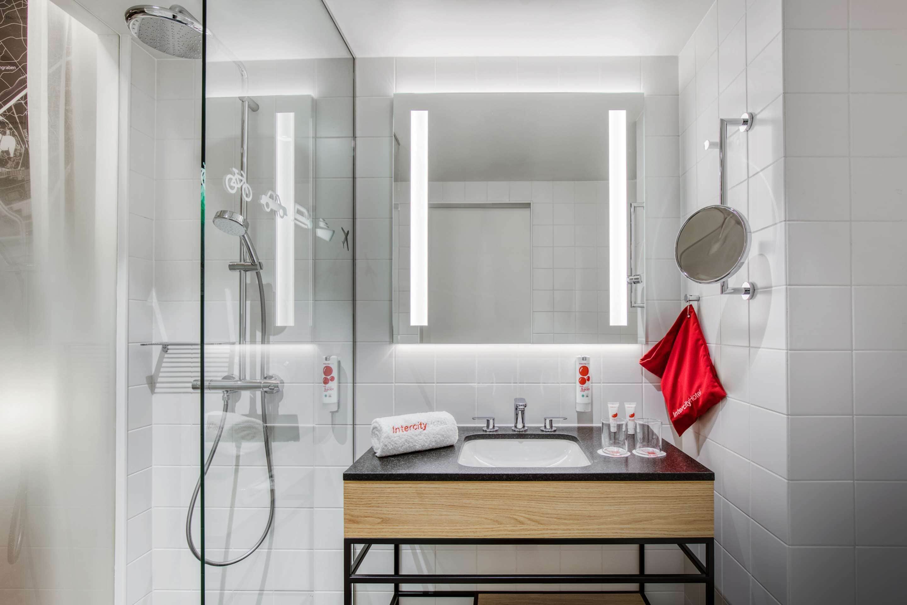 A modern bathroom with a glass-enclosed shower, a wooden vanity with a sink, and a large mirror.