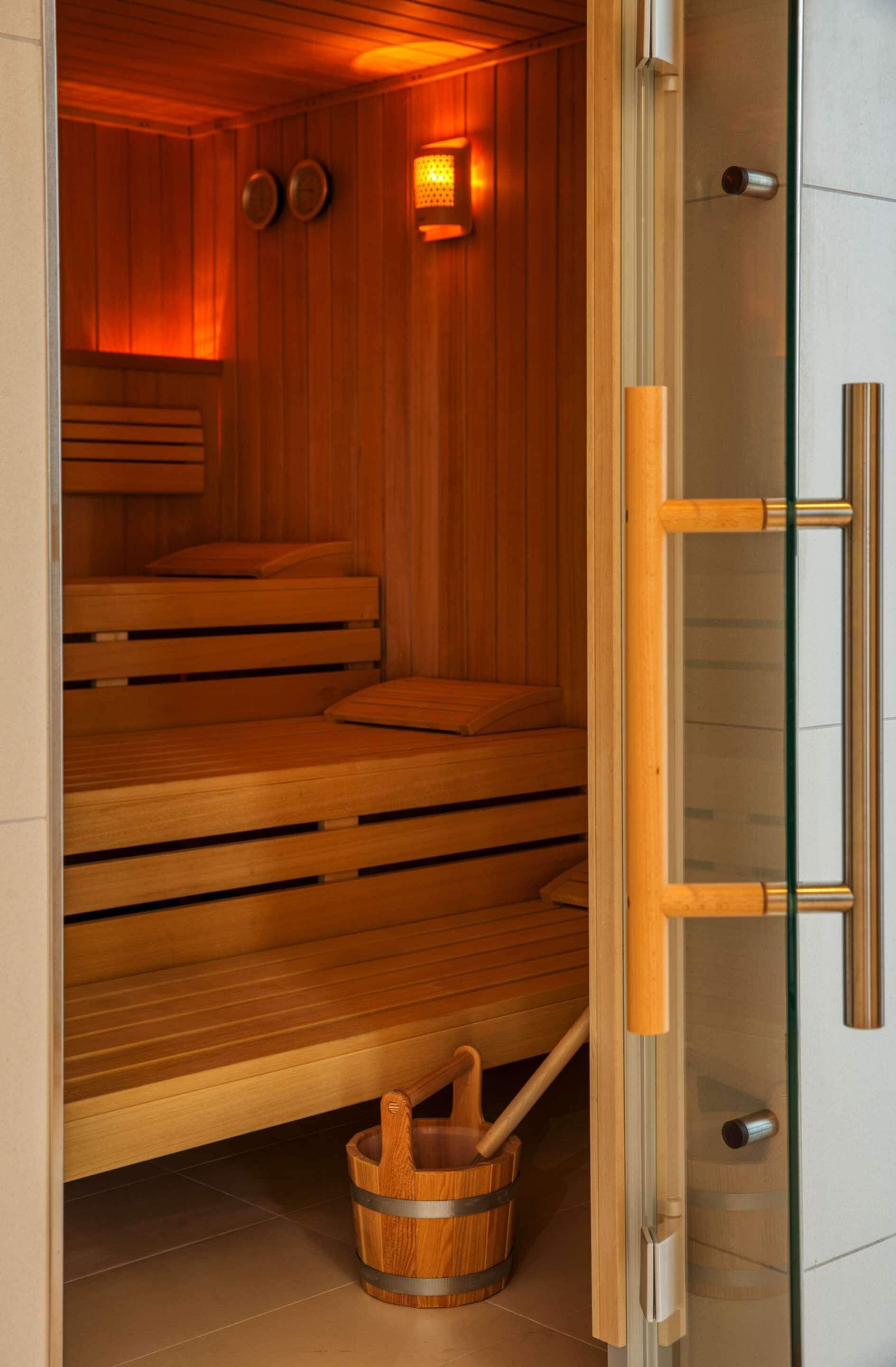 Una sauna con bancos de madera y un cubo.
