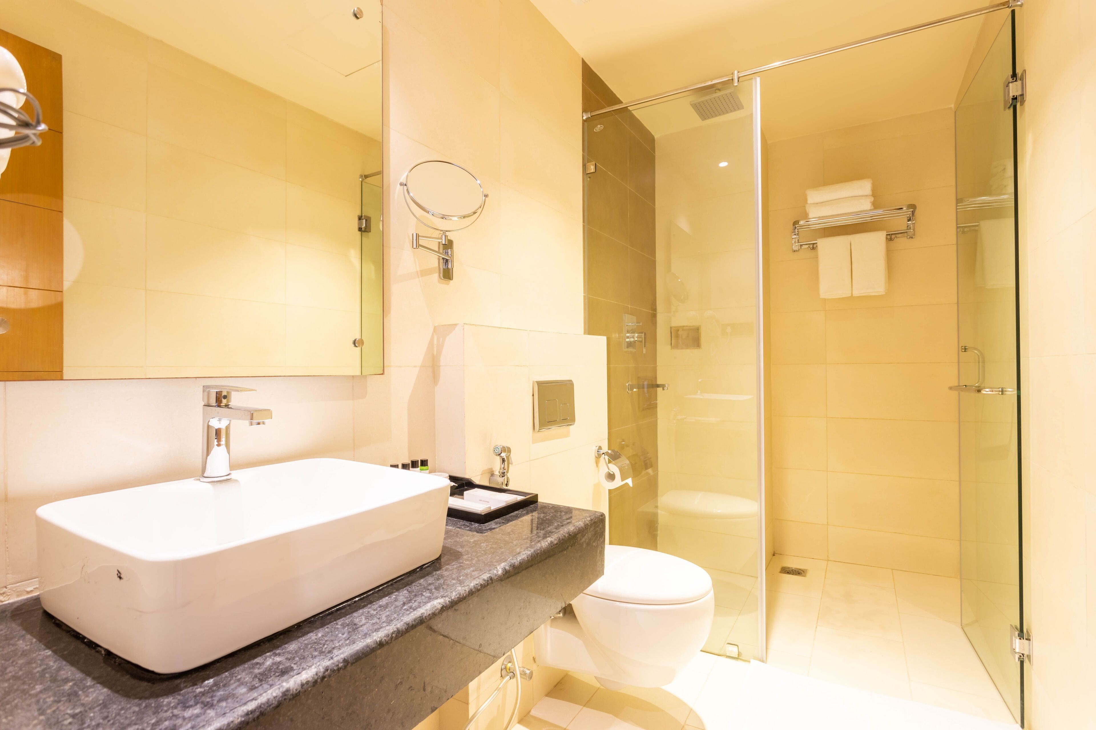 Een moderne badkamer met een groot wit wastafelmeubel, een douchecabine met glazen wanden en een toilet.