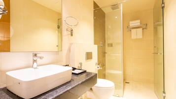 Een moderne badkamer met een groot wit wastafelmeubel, een douchecabine met glazen wanden en een toilet.