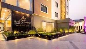 Exterior del Hotel Da Flamingo, con una fachada moderna, una entrada bien iluminada y un jardín ajardinado con asientos.