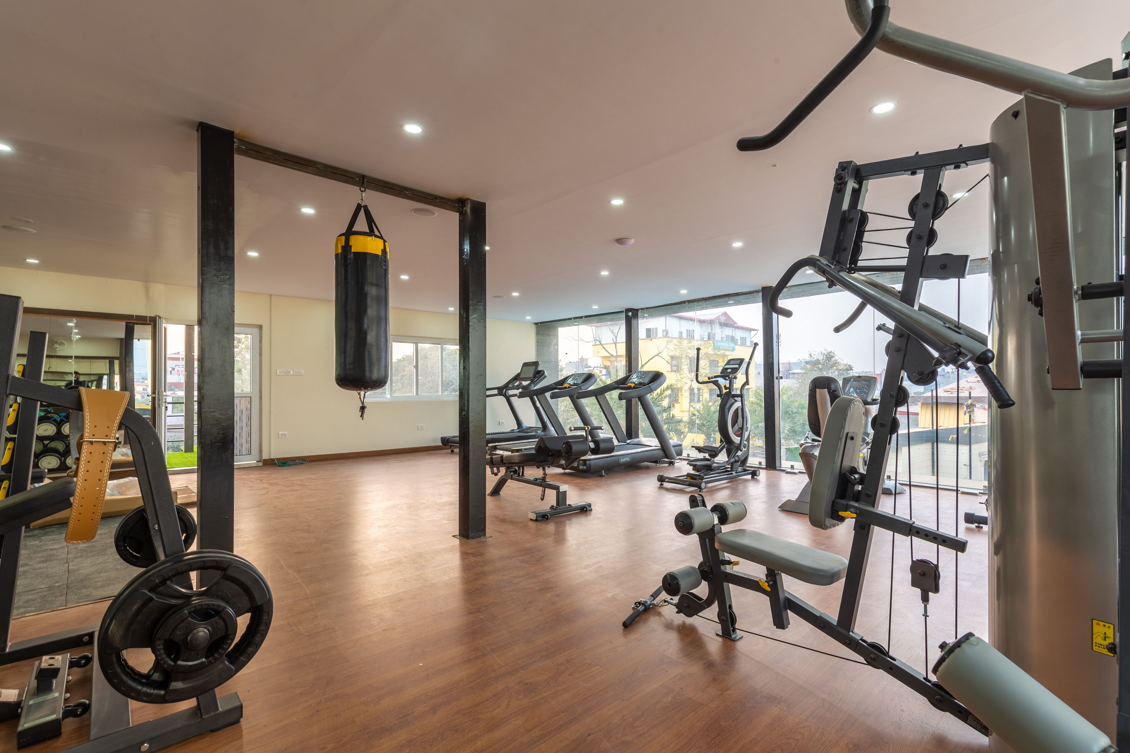 Un gimnasio amplio con máquinas de cardio, equipo de levantamiento de pesas y un saco de boxeo.