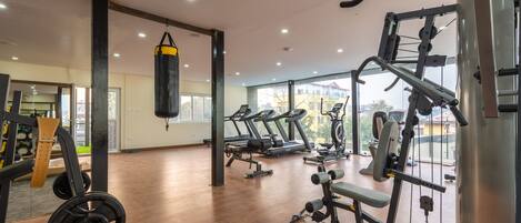 Un gimnasio amplio con máquinas de cardio, equipo de levantamiento de pesas y un saco de boxeo.