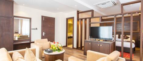 Una habitación de hotel moderna con sofá, televisión y un mueble de madera.