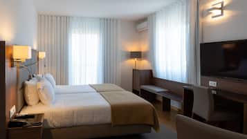 A hotel room with a bed, bedside tables, a desk, a chair, a TV, and curtains.