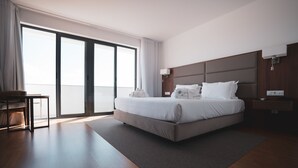 A modern hotel room with a large bed, a desk, and a view of the outdoors through a sliding door. - Hotel Freixo Douro Superior (Freixo de Espada a Cinta)