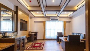 Una sala de estar moderna con televisor de pantalla plana, comedor y una zona de estar con sofá y sillones.
