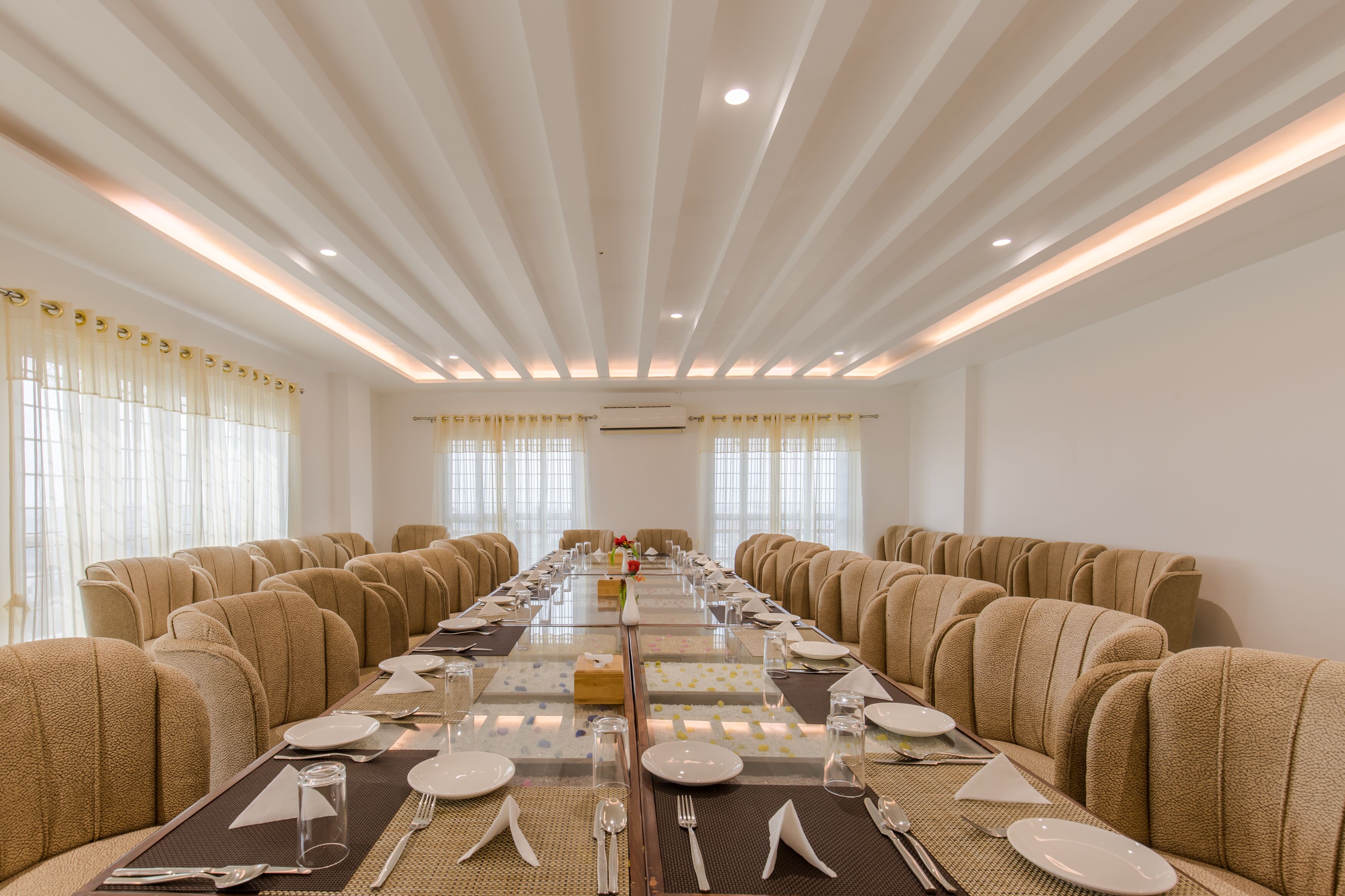 A conference room with a long table set for a meeting, surrounded by sofas.
