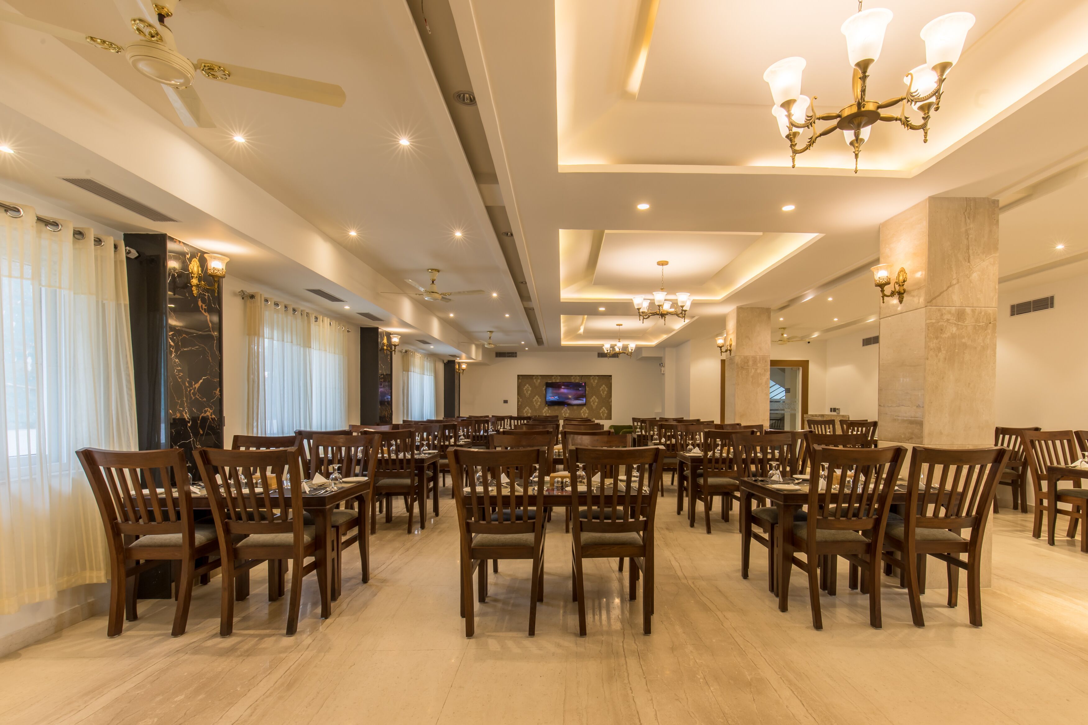 A spacious dining area with multiple tables and chairs, ceiling fans, and recessed lighting.