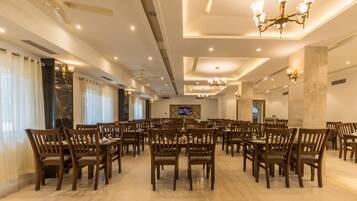 A spacious dining area with multiple tables and chairs, ceiling fans, and recessed lighting.