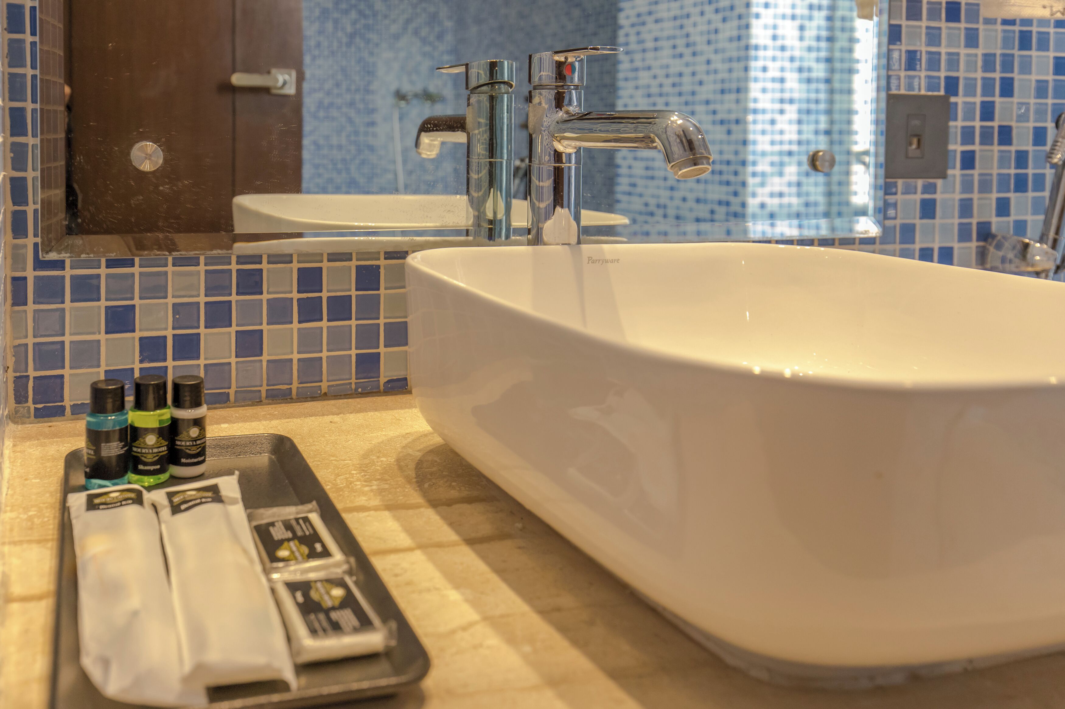 A bathroom with a white bathtub, a mirror, and a sink. There are toiletries on the counter.