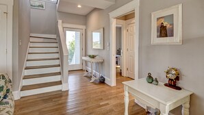 A staircase leading to a second floor, a small table with decorative items, and a framed picture on the wall. - Bald Head Island. Oceanfront 2nd Row. 4 bedrooms. 3.5 baths. BHI Club access. (Bald Head Island)