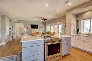 A modern kitchen with a built-in oven, white cabinets, and a dining area with a table and chairs.