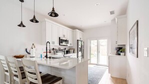 A modern kitchen with white cabinetry, a central island, and pendant lighting.