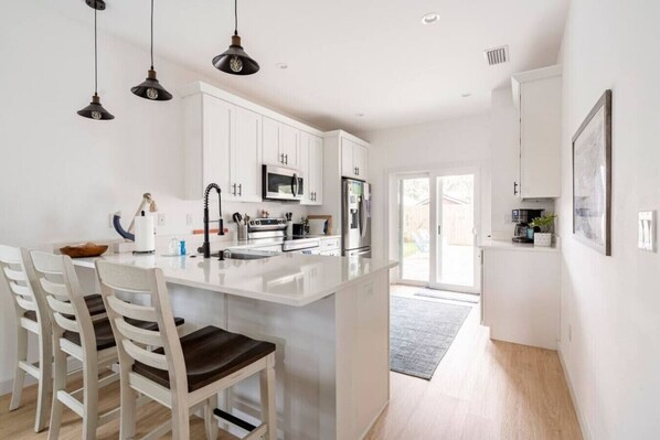 A modern kitchen with white cabinetry, a central island, and pendant lighting.