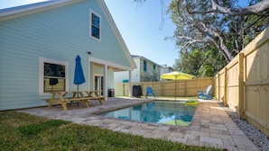A backyard with a swimming pool, a picnic table, and a wooden fence.