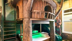 A treehouse-style play area with a slide, a ladder, and a green-lit playpen. - Rare Home w Golf Simulator, Sci-Fi Theme BR, Arcade, Theater & Gym - Near Parks (Davenport)