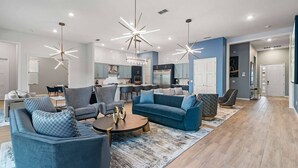 Un salon moderne avec un canapé bleu, des fauteuils gris et une table basse.