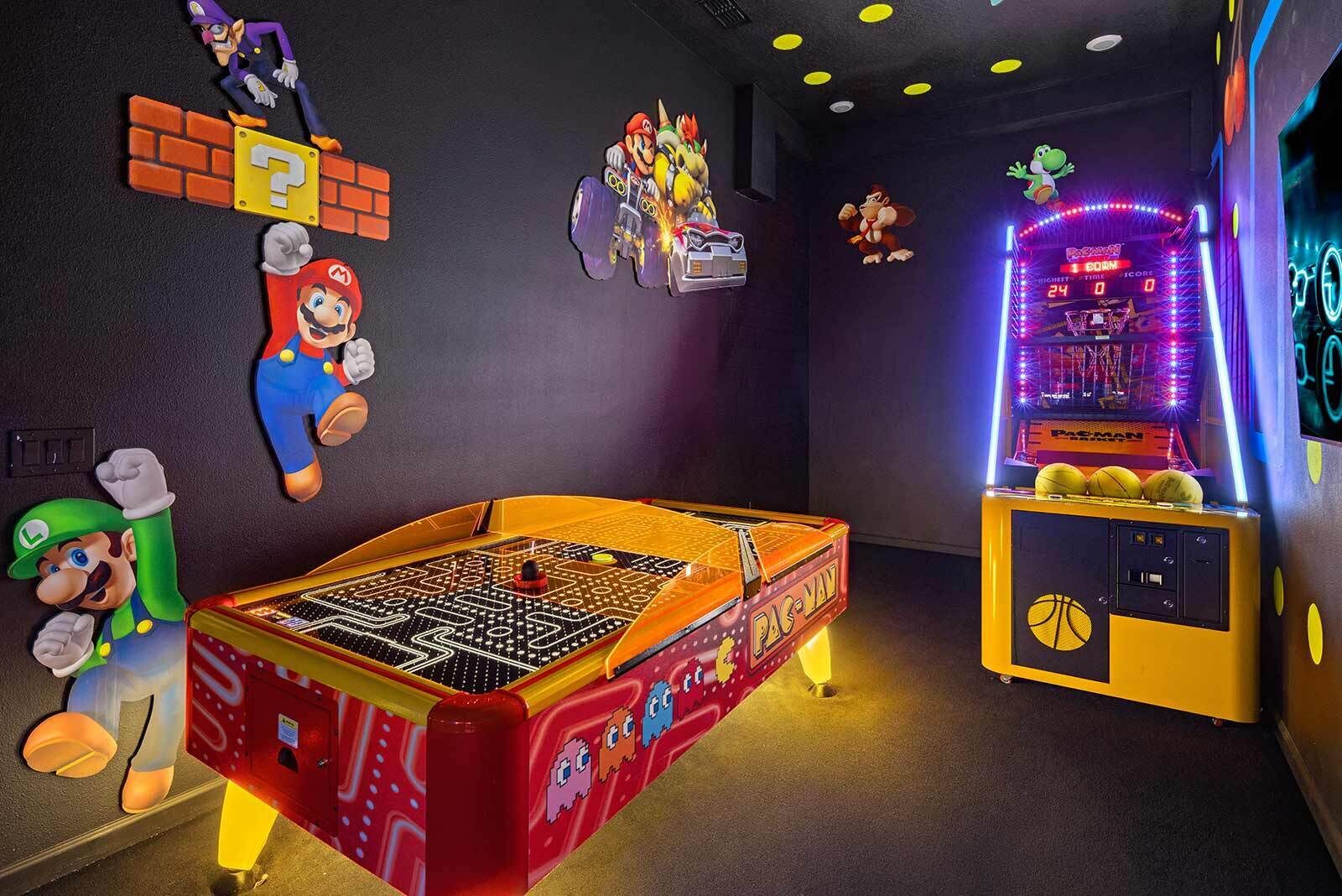 A room with a foosball table, a Pac-Man arcade machine, and Mario and Luigi decorations.