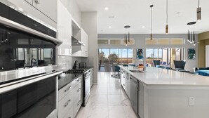 Een moderne keuken met een groot eiland, roestvrijstalen apparatuur en uitzicht op de omgeving.